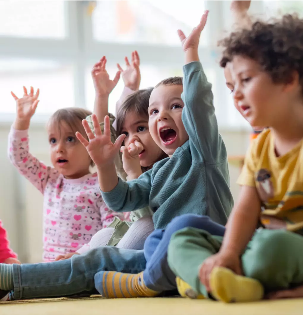Young children playing a game raising their hands